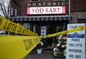 A historic yogurt shop marked by police tape and memorial flowers, representing the 1991 Yogurt Shop Murders case.