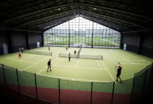 Interior view of a modern padel facility featuring illuminated courts and players in action.